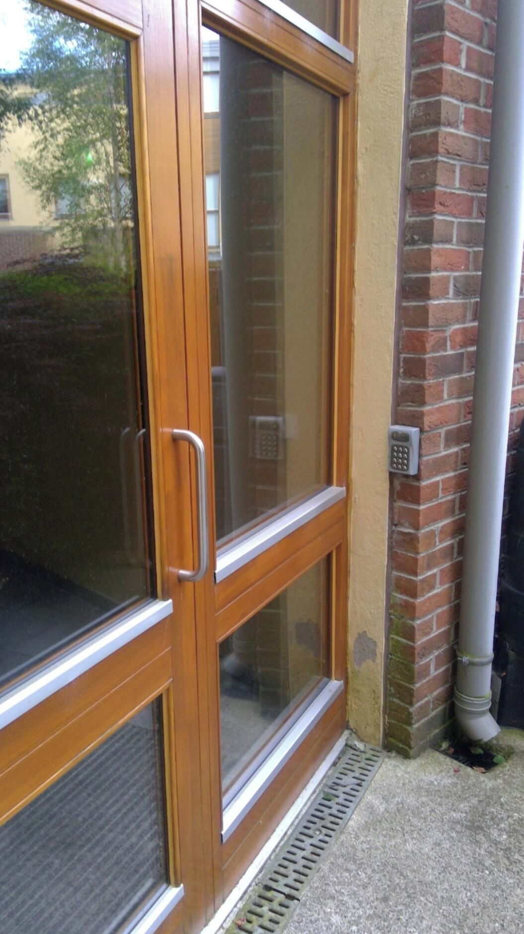 A wooden door with a glass panel, a metal handle, and a keypad lock.