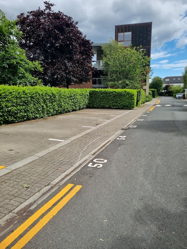 A residential street with a clear road, a speed limit sign, and a modern building in the background.