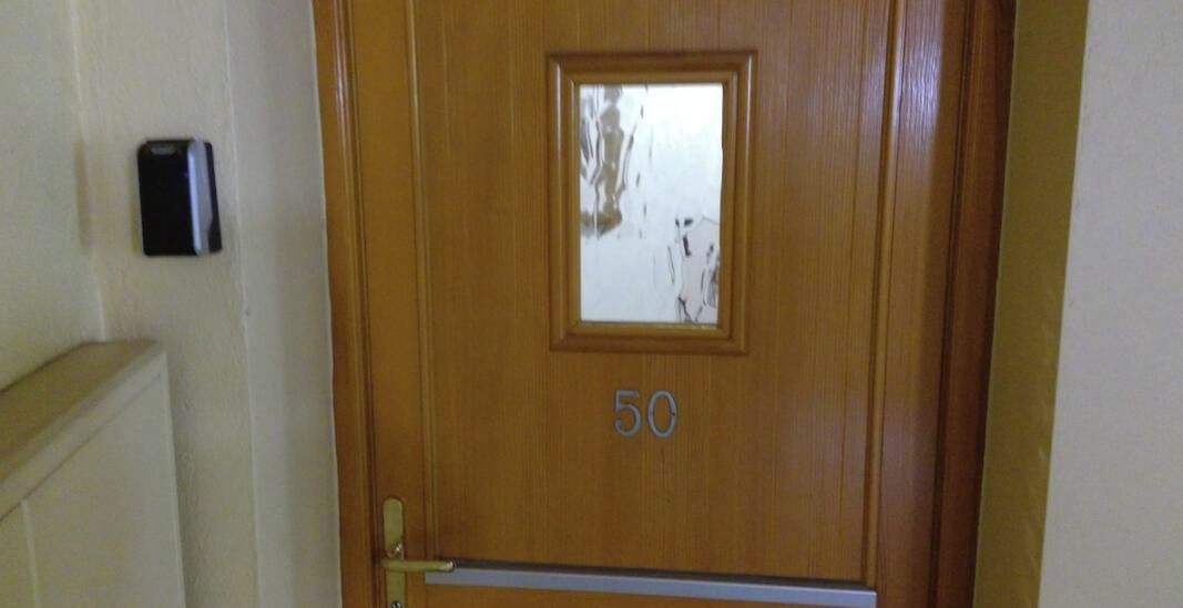 A wooden door with the number 50, a small window, and a doorbell.