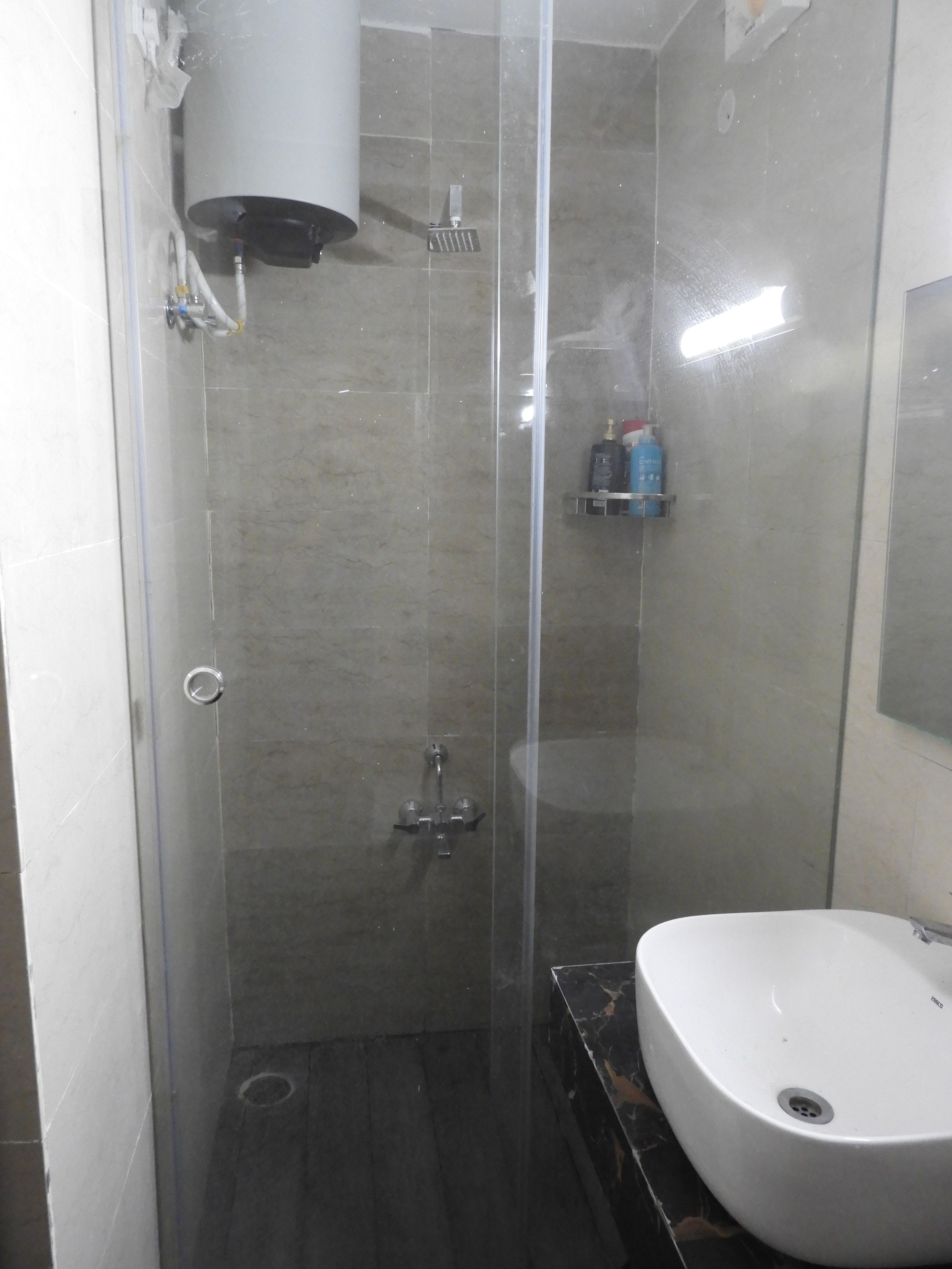 Un baño con ducha envuelta en vidrio, un lavamanos blanco y un espejo en la pared.