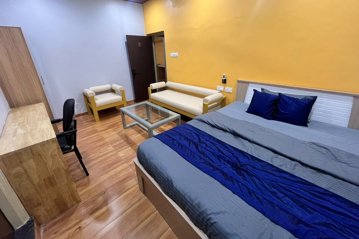 Um quarto com cama, poltrona, sofá e escrivaninha.