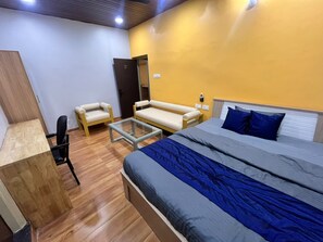 Um quarto com cama, poltrona, sofá e escrivaninha.