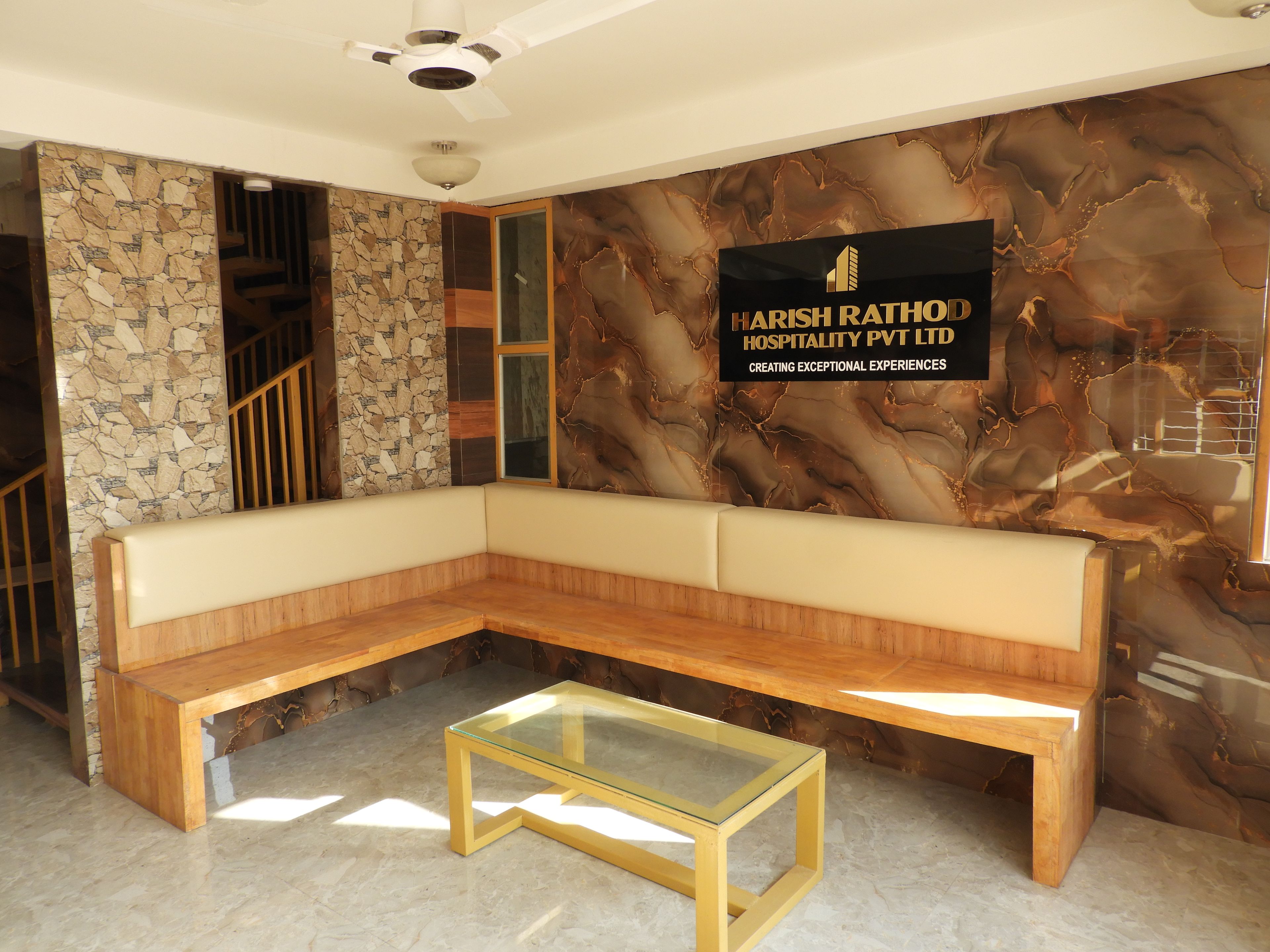 Un interior moderno con una pared de piedra, un banco de madera y una mesa de vidrio.