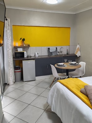 Et kompakt hotelværelse med tekøkken, spiseplads og seng.