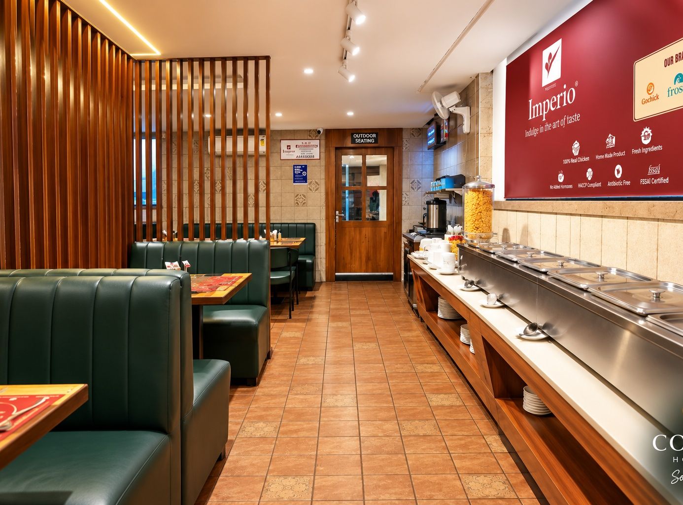 A restaurant with green upholstered booths, a buffet area with various food items, and a sign indicating outdoor seating.