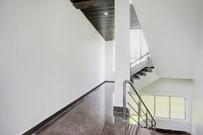 Un interior moderno con una escalera que conduce a un nivel superior, un piso pulido y un amplio ventanal que proporciona luz natural.