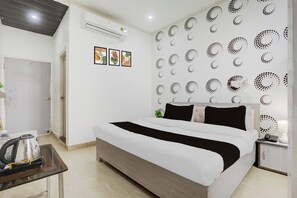 Una habitación de hotel con una cama, una mesita de noche, un hervidor y una pared con diseños circulares.