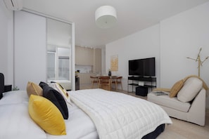 A modern bedroom with a bed, a sofa, a television, and a dining area. - Warszawa | Krochmalna 61 | Modern Studio | Air Conditioning (Warszawa)