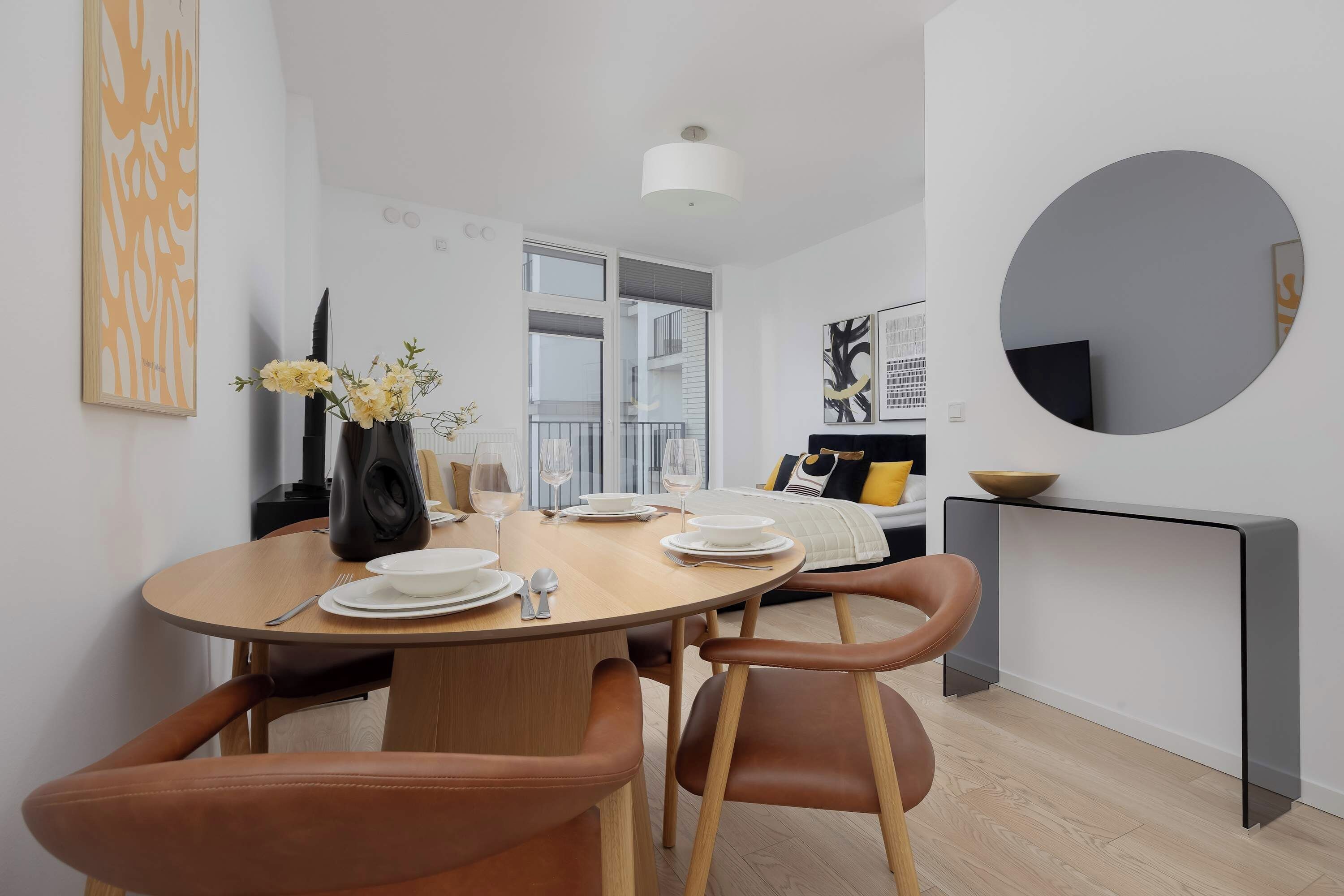 A modern dining area with a round table, chairs, and a vase with flowers.