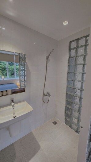 A bathroom with a shower, a sink, and a window with a view. - D1 Heart · Cityview & Rooftop · Kanso @ Cozinema (Ben Thanh, District 1)