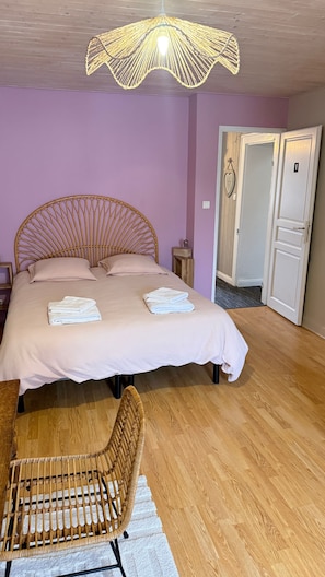 Un dormitorio con cama, una silla, piso de madera y una puerta.
