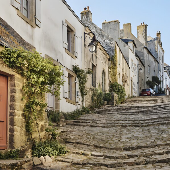 Rua de paralelepípedos ladeada por edifícios históricos com paredes de pedra e janelas tradicionais.