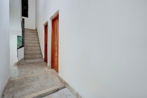 Un pasillo estrecho con una escalera que conduce a una puerta.