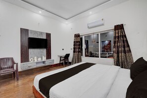 Une chambre d’hôtel moderne avec un grand lit, un bureau et un téléviseur fixé au mur.