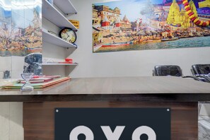 Un comptoir d’accueil avec une horloge, un calendrier et une photographie encadrée représentant un paysage fluvial.