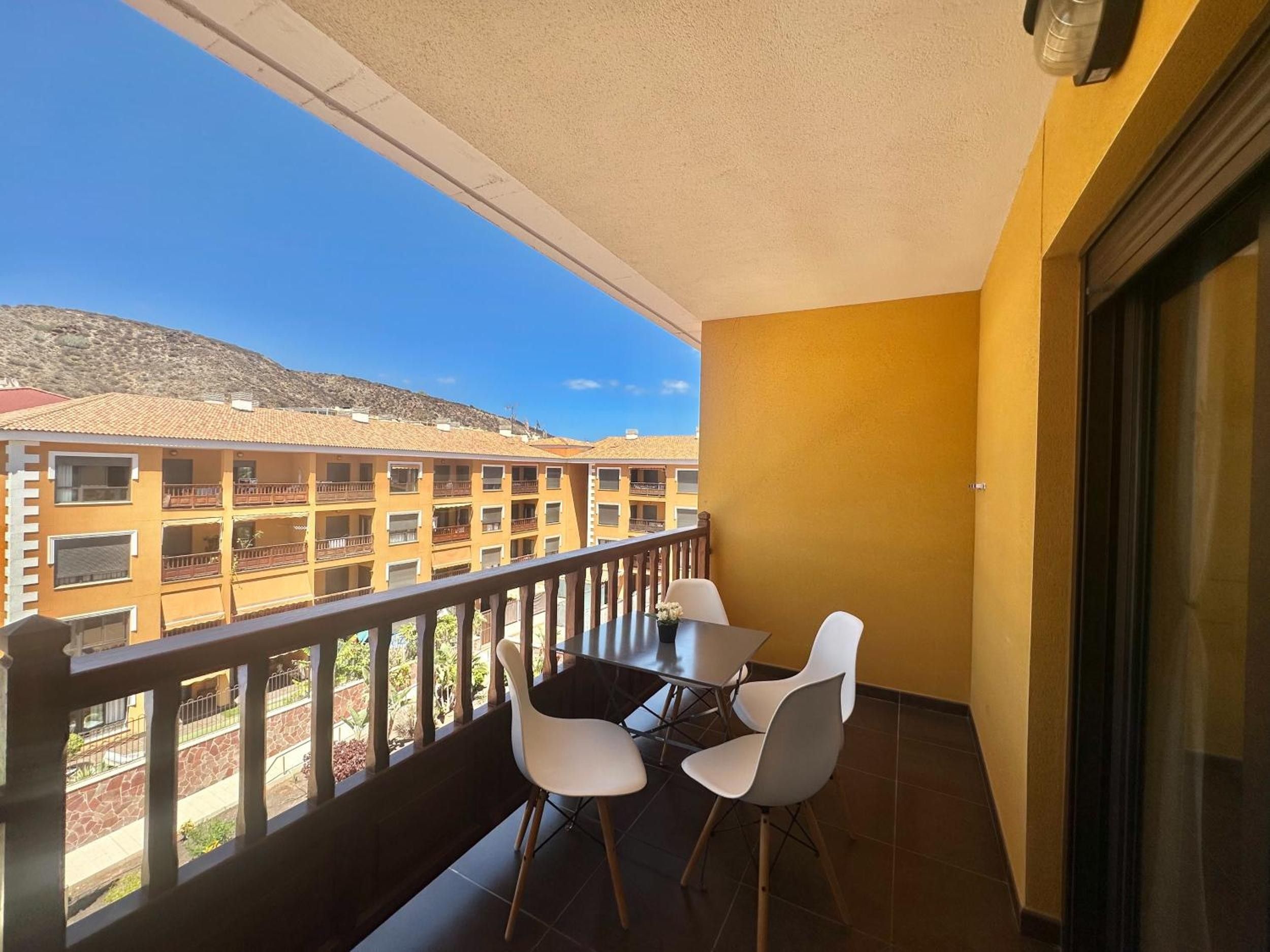 A balcony with a table and chairs, overlooking a building complex.