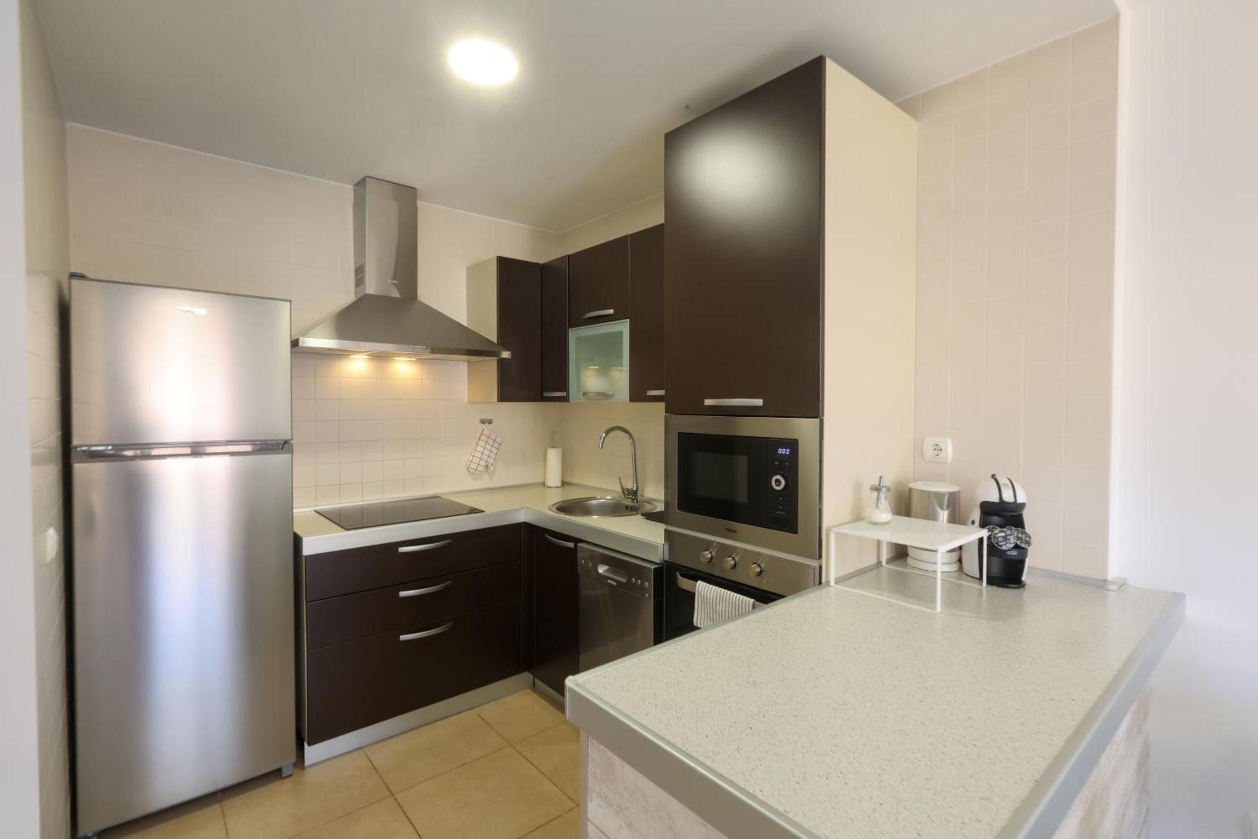 A modern kitchen with a stainless steel refrigerator, a built-in oven, and a microwave.