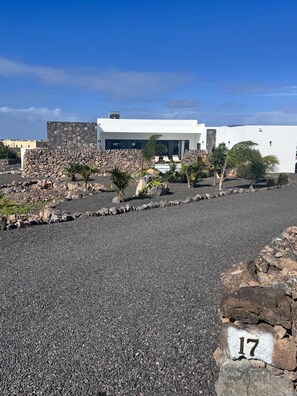 Un bâtiment moderne doté d’un mur en pierre et d’une zone pavée avec une pierre portant un numéro.