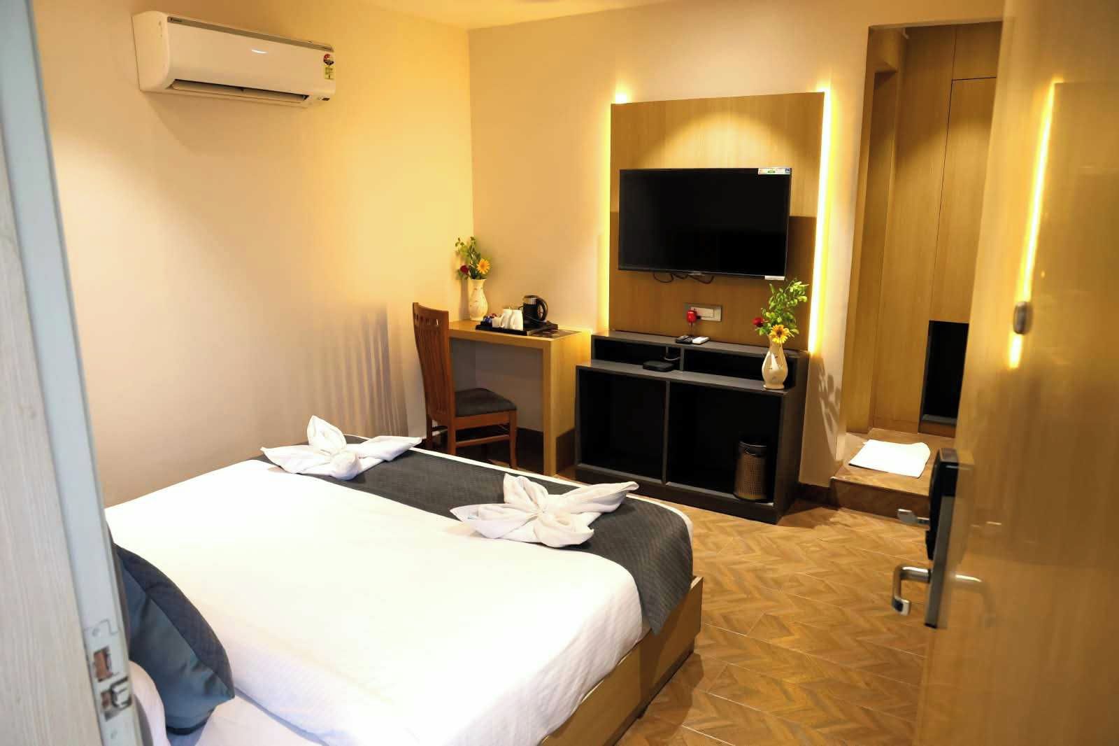 Habitación de hotel con cama, escritorio, silla, televisión y aire acondicionado.