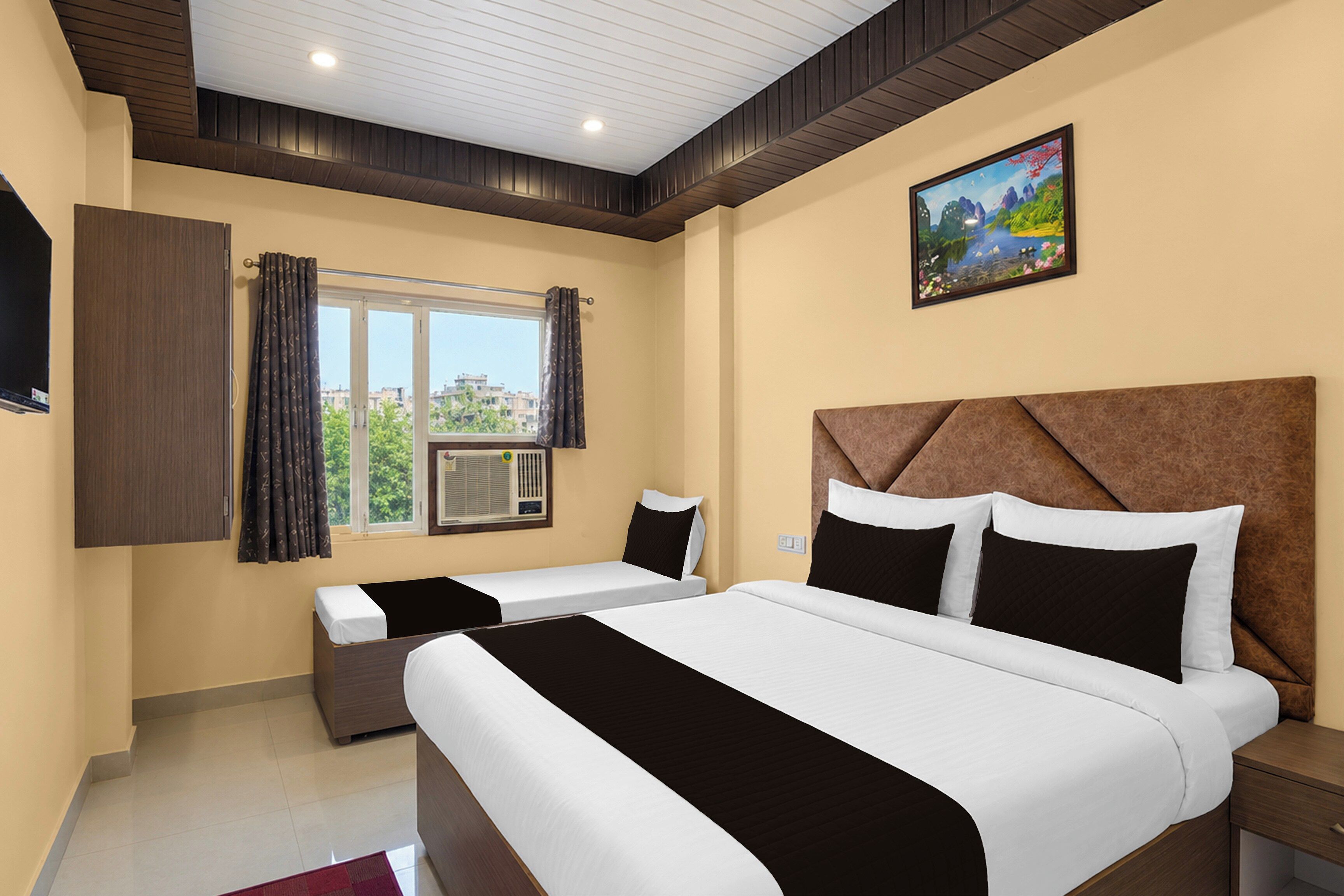 Habitación de hotel con dos camas, un ventanal grande, un cuadro en la pared y un equipo de aire acondicionado.