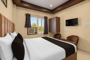 Une chambre d’hôtel avec un lit, une télévision, une armoire et une fenêtre avec des rideaux.