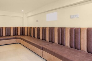 Un sofá modular largo en forma de L en una habitación con piso de baldosas y una pared lisa.
