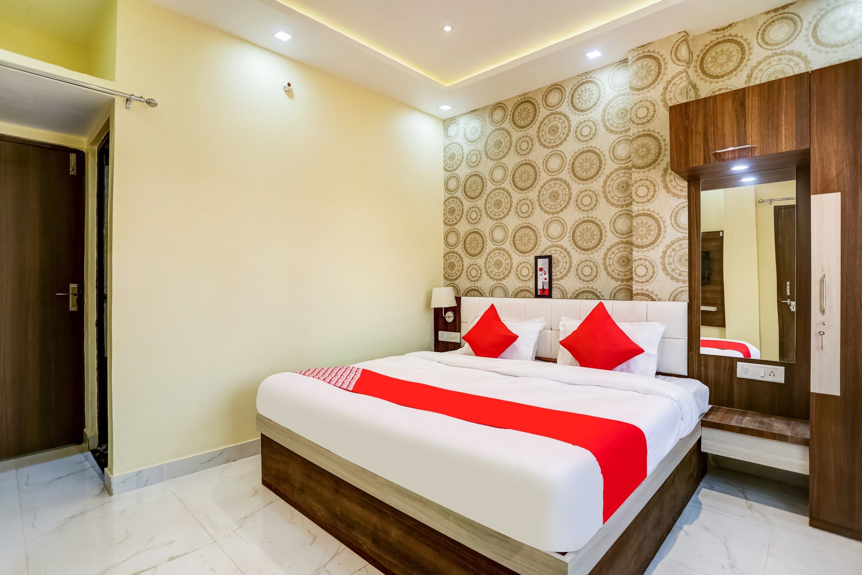 A hotel room with a large bed, a wooden headboard, a mirror, and a patterned wall.