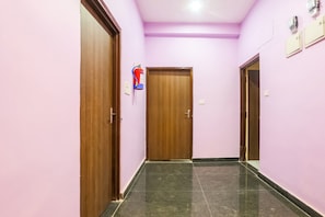 Un pasillo con puertas de madera, un extintor y suelo de baldosas.