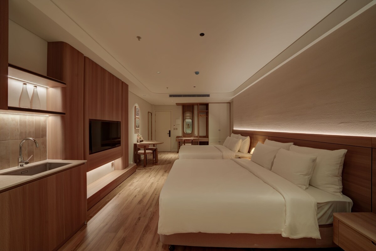 Een moderne hotelkamer met een groot bed, een televisie, een houten kast en een badkamer.
