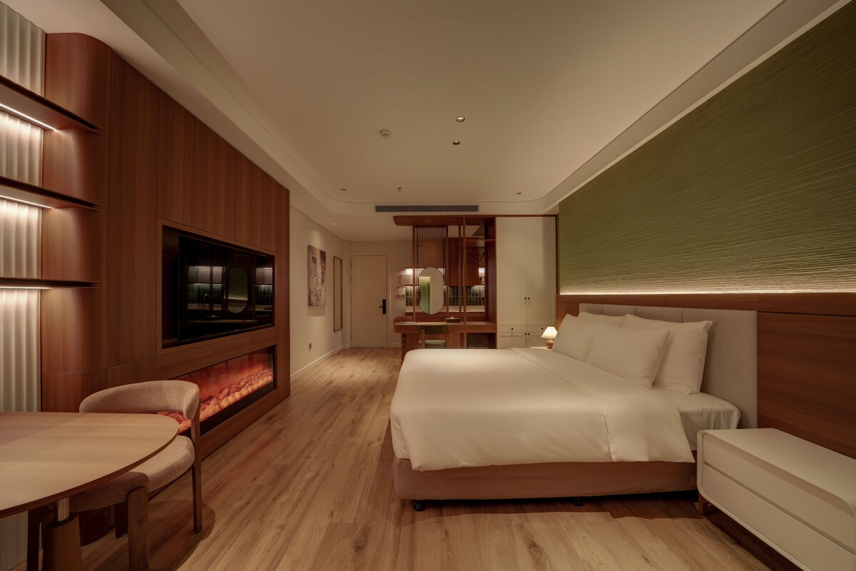 Een moderne hotelkamer met een groot bed, een bureau, een televisie en een zithoek.