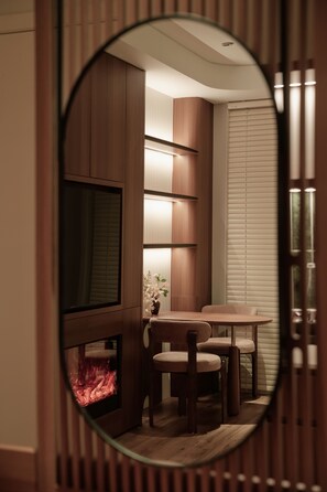 Een gezellige kamer met een open haard, een televisie en een eethoek met stoelen en een tafel.