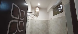 Une salle de bain équipée d’une douche, d’un porte-serviettes et d’un luminaire fixé au mur.