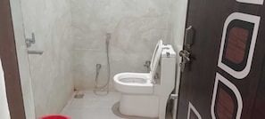 Une salle de bain comprenant des toilettes, une douche et une porte ornée d’un motif décoratif.