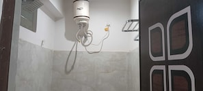 Un baño con ducha, pared blanca y puerta de diseño geométrico.