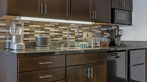 Una cocina con armarios de madera oscura, encimera de acero inoxidable, licuadora, hervidor y tostadora.