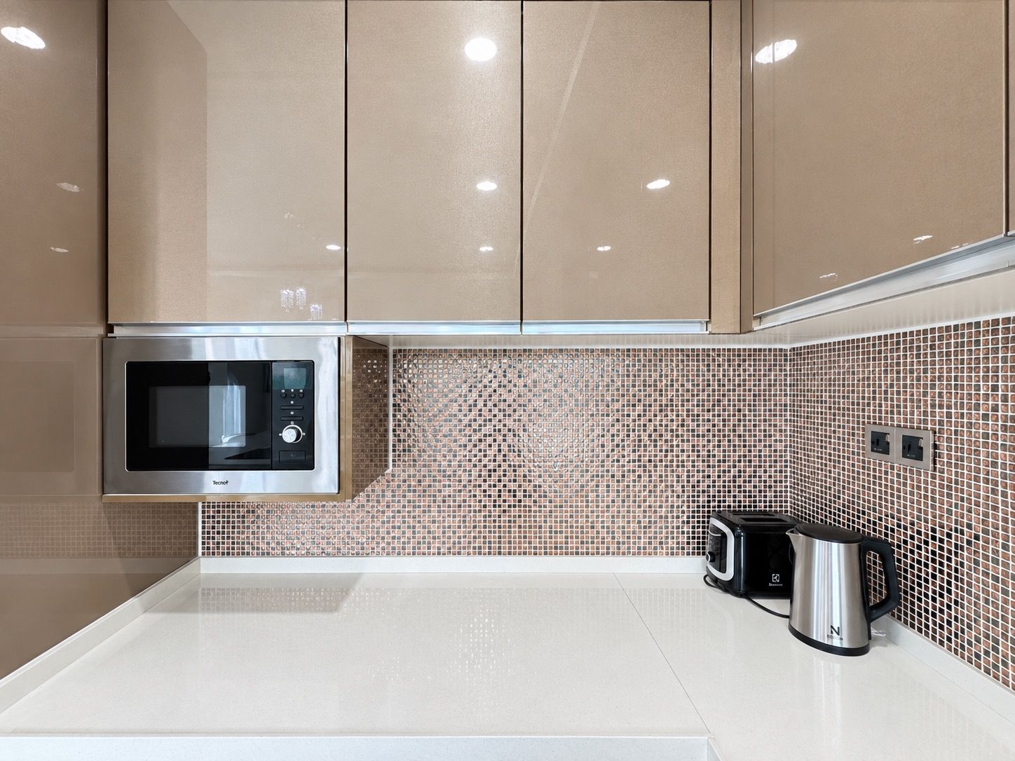 Una cocina moderna con microondas, hervidor y tostadora sobre la encimera.