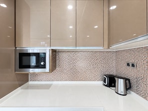 Una cocina moderna con microondas, hervidor y tostadora sobre la encimera.