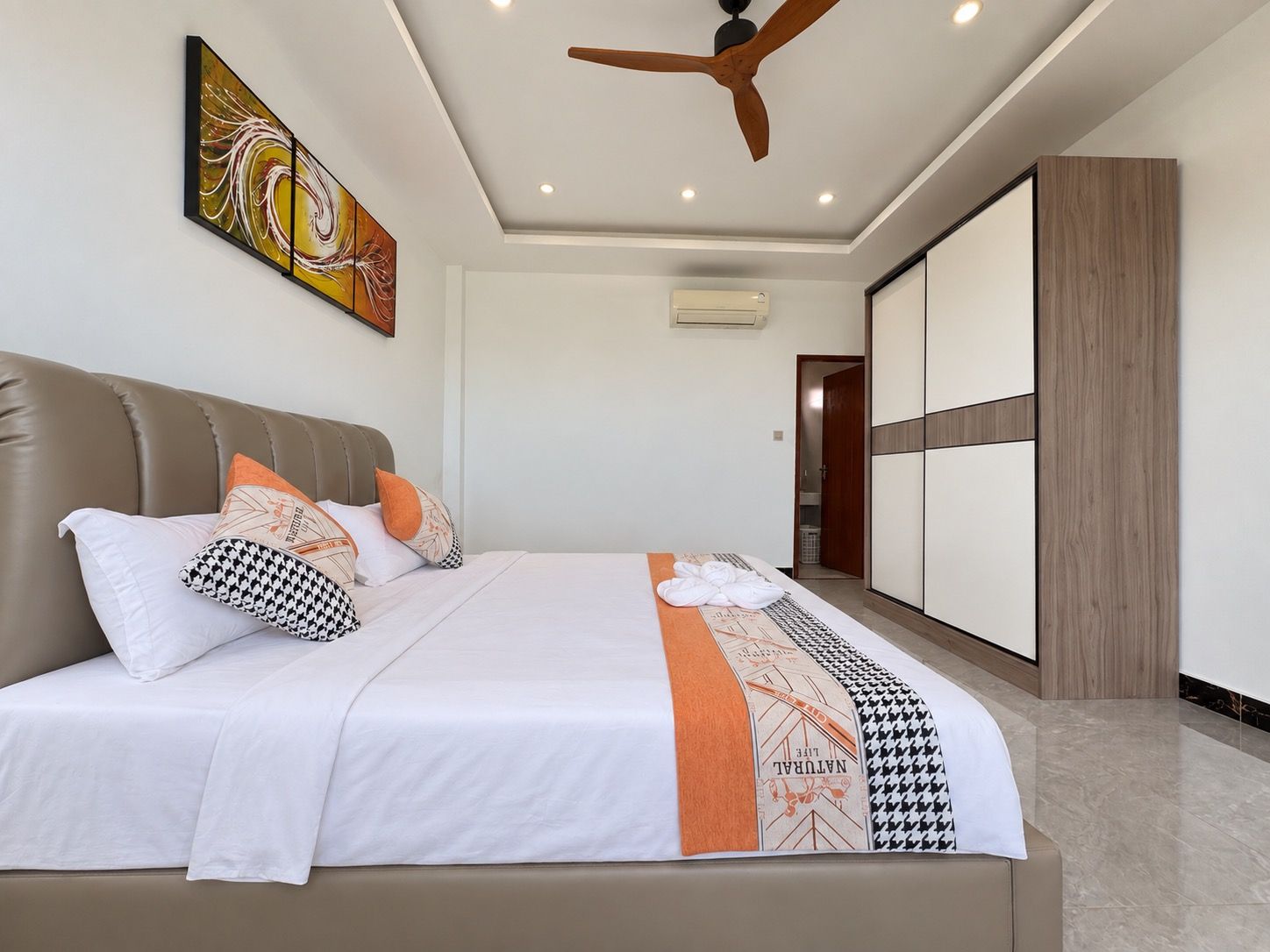 Een moderne slaapkamer met een bed, een plafondventilator en een schilderij aan de muur.