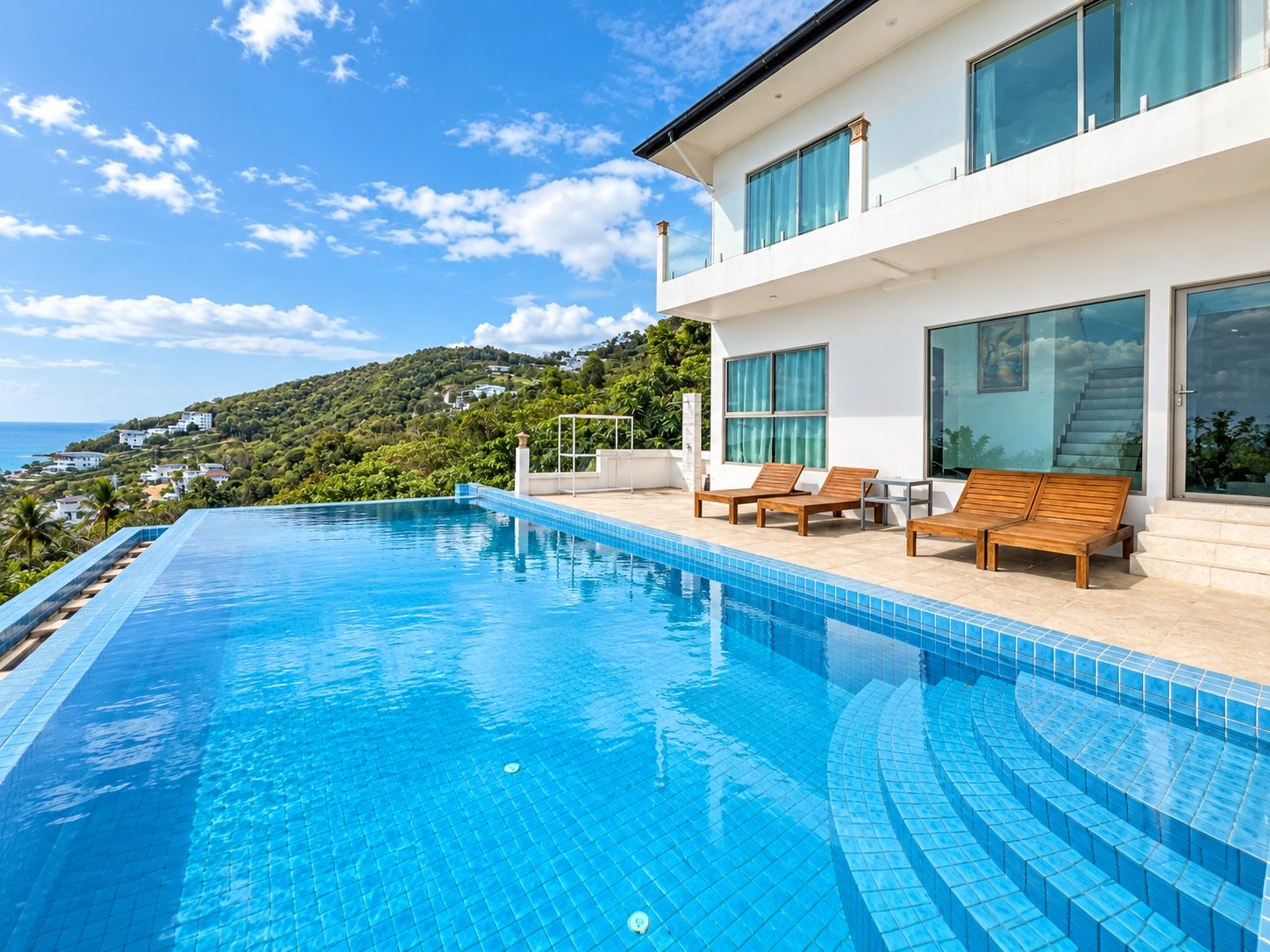 Un área de piscina moderna con vista despejada al océano y una ladera.