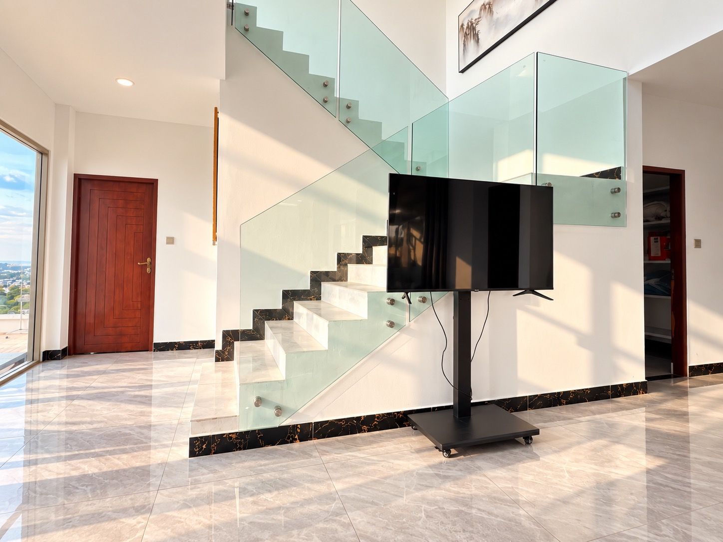 Een modern interieur met een trap, een flatscreen televisie en een deur.