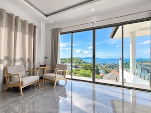 Una sala de estar moderna con un amplio ventanal corredera que da a un balcón con vistas a la ciudad.