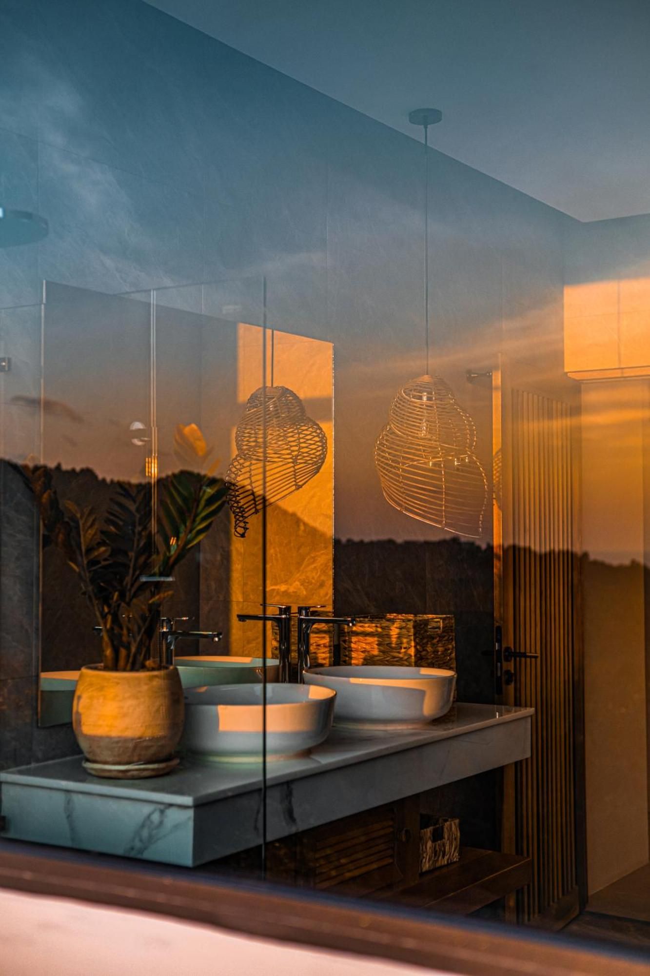 Une salle de bain avec un grand miroir, deux lavabos et un luminaire suspendu.