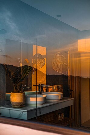 Une salle de bain avec un grand miroir, deux lavabos et un luminaire suspendu.