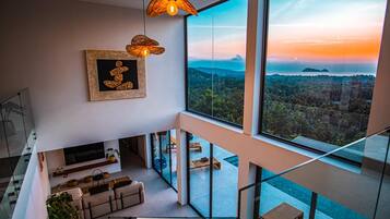 Un interior moderno con un gran ventanal que da a un paisaje, un sofá y una obra de arte enmarcada.