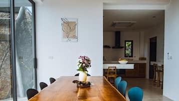 Un espace repas moderne avec une grande table en bois, des chaises bleues et un vase rempli de fleurs.