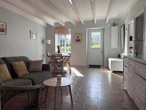 Una habitación con una mesa de comedor, sillas, un sof á, una mesita redonda y un armario.
