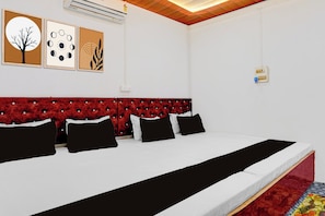 A hotel room with a large bed, a red upholstered headboard, and wall-mounted air conditioning units. - Hotel O The Friends Table Guest House (Varanasi)