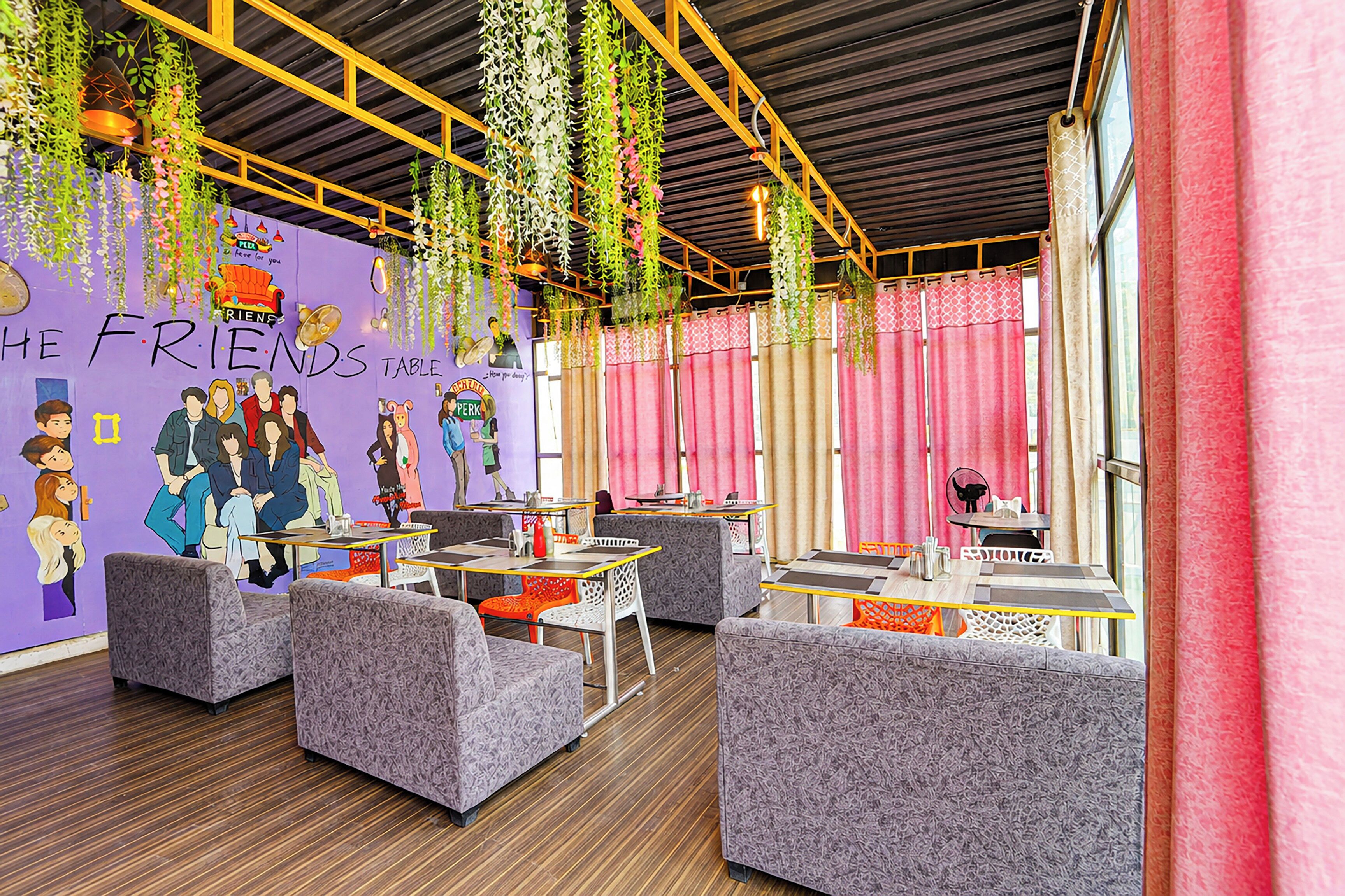 Un intérieur de restaurant dynamique, agrémenté de plantes suspendues, de peintures murales colorées et de mobilier moderne.