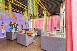 A vibrant restaurant interior with hanging plants, colorful murals, and modern furniture. - Hotel O The Friends Table Guest House (Varanasi)