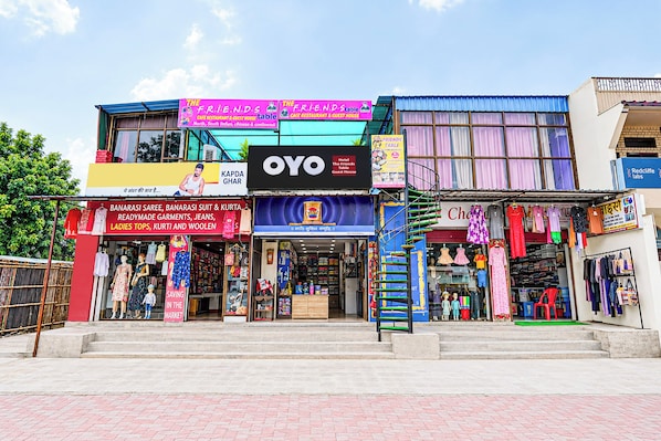 A multi-story building with various shops on the ground floor, including a clothing store and a cafe. - Hotel O The Friends Table Guest House (Varanasi)